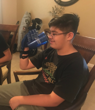 a boy holding a cup with a blue prosthetic hand