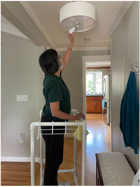 a woman using the stool and rails to change a lightbulb