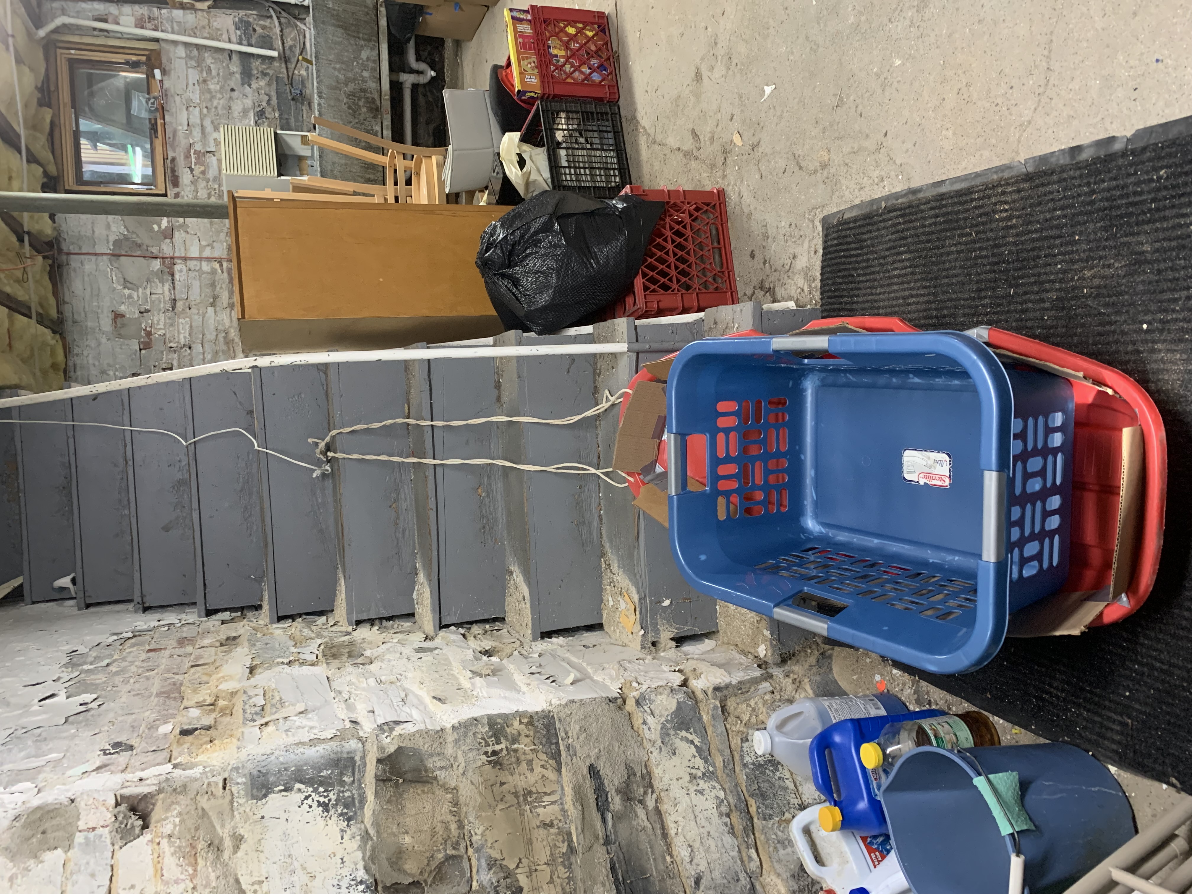 a sled with a laundry basket in it at the bottom of a set of stairs