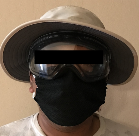 front view of a person wearing wearing goggles, hat, and a face mask